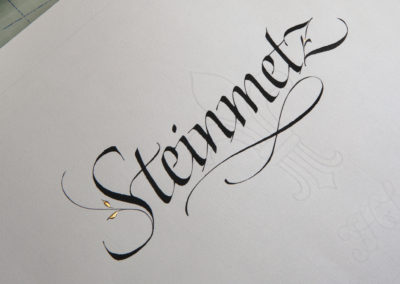 Name handwritten in calligraphy (Italic) with gold leaf.